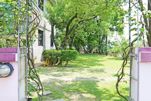 a yard with trees and a house with a fence at Kaohsiung Meinong Rabbit Paul Homestay B&B in Meinong