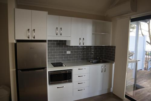 a kitchen with white cabinets and a stainless steel refrigerator at NRMA Port Macquarie Breakwall Holiday Park in Port Macquarie