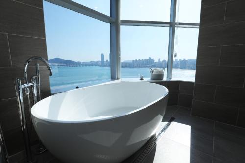 un bagno con vasca e ampia finestra di H Avenue Gwanganri Beach a Busan