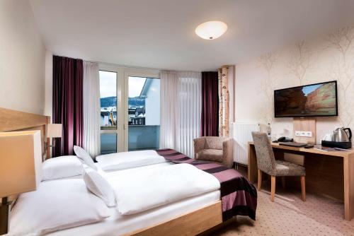 ヴィリンゲンにあるBest Western Plus Hotel Willingenのベッドとデスクが備わるホテルルームです。