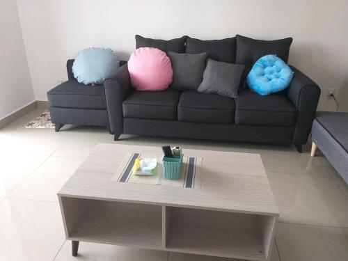 a living room with a couch with pillows and a coffee table at Kempas Indah @ The Secret Garden Homestay in Johor Bahru