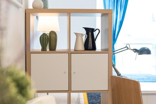 a book shelf with vases and a lamp at HaPPy INN Studio Historic center, Self check-in, AC, Parking in the undergrnd Garage, in Vilnius