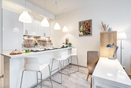a kitchen with a bar with white chairs and tables at HaPPy INN Studio Historic center, Self check-in, AC, Parking in the undergrnd Garage, in Vilnius