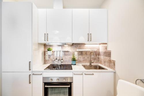 a kitchen with white cabinets and a sink at HaPPy INN Studio Historic center, Self check-in, AC, Parking in the undergrnd Garage, in Vilnius