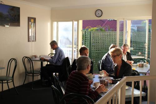 a group of people sitting at tables in a restaurant at Toowong Central Motel Apartments in Brisbane