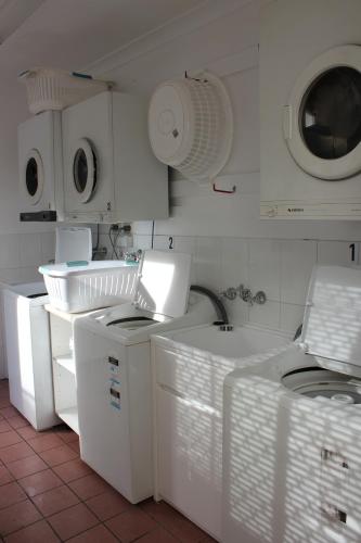 a kitchen with white appliances and a washer and dryer at Toowong Central Motel Apartments in Brisbane