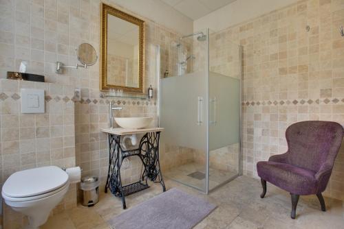 a bathroom with a toilet and a sink and a chair at Rue Galilee in Marseillan