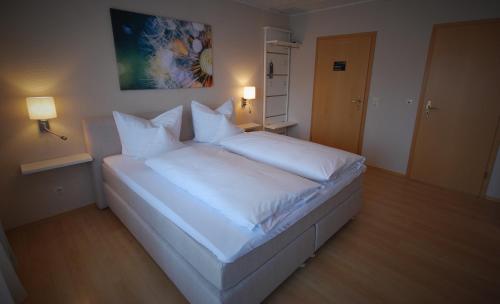 a bedroom with a white bed with white sheets and pillows at Hotel Colosseum in Rheinböllen
