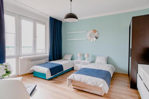 dwa łóżka w sypialni z niebieskimi ścianami w obiekcie Prudentia Apartments Grenadierów w Warszawie