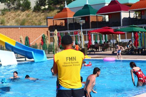 a man in a pool with people playing in the water at Spring Hotel in Novxanı
