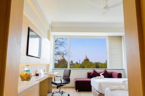 a hotel room with a bed and a large window at Gemini Continental, Hazratganj in Lucknow