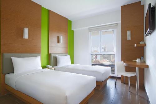 two beds in a room with a green wall at Amaris Hotel Embong Malang - Surabaya in Surabaya