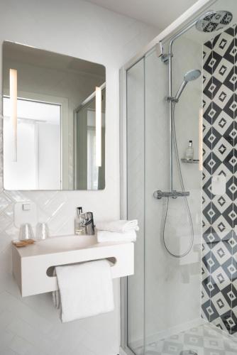 a white bathroom with a sink and a shower at Hotel des Lys in Versailles