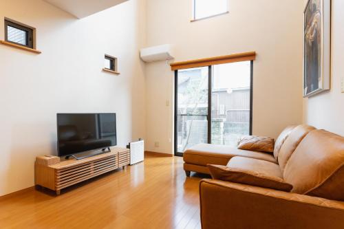 a living room with a couch and a flat screen tv at Ecol Beppu in Beppu