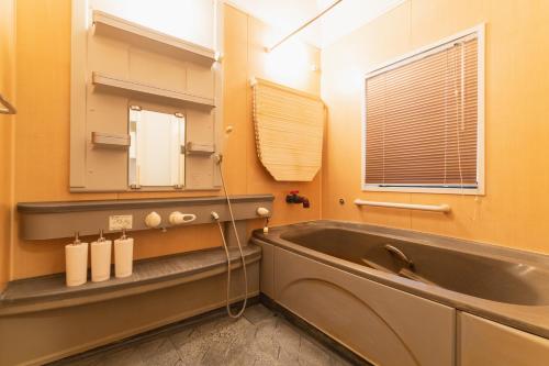 a bathroom with a tub and a sink and a mirror at Ecol Beppu in Beppu