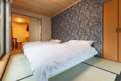 a bedroom with two beds and a wall at Ecol Beppu in Beppu
