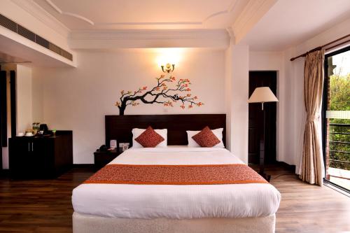 a bedroom with a large bed with a tree on the wall at Park Village Resort by KGH Group in Kathmandu