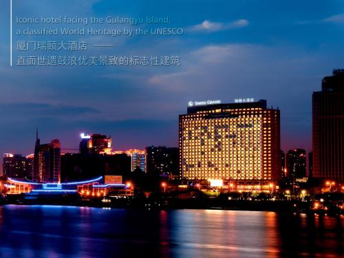 ein beleuchtetes Gebäude in einer Stadt in der Nacht in der Unterkunft Swiss Grand Xiamen-Harbour View in Xiamen
