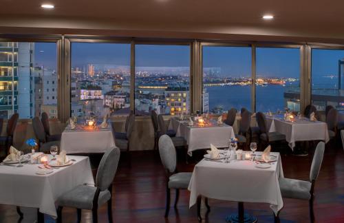 een restaurant met tafels en stoelen en uitzicht op de stad bij Taksim Square Hotel in Istanbul