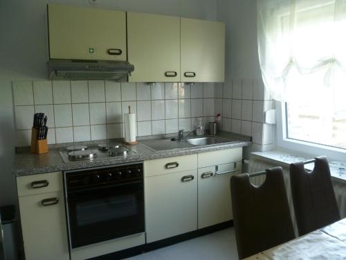 cocina con fogones, fregadero y ventana en Ferienwohnung Kutscherhof Bartels en Bispingen