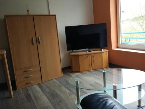 a living room with a tv and a glass table at Ferienappartement Trier in Trier