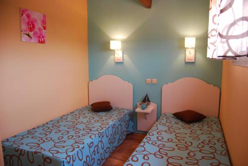 - 2 lits dans une chambre aux murs bleus et roses dans l'établissement Lagrange Grand Bleu Vacances – Résidence Les Jardins de Neptune, à Saint-Cyprien