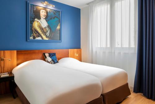 a bedroom with a large bed with a painting on the wall at Hotel des Lys in Versailles