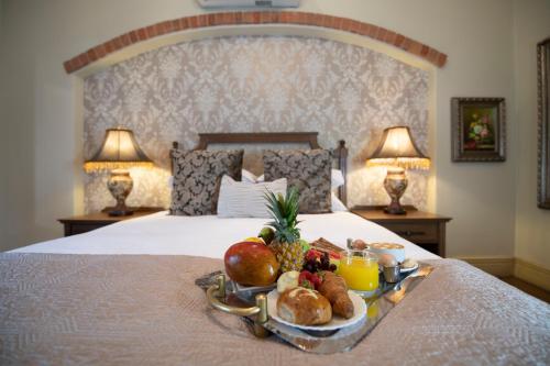 a tray of fruit and bread on a bed at Three Rivers Lodge and Villas in Vereeniging