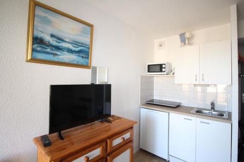 une cuisine avec une télévision à écran plat sur un comptoir dans l'établissement BEA122 - Appartement vue mer !, à Canet