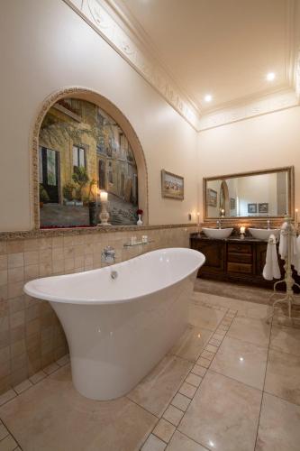 a large bathroom with a tub and a large mirror at Three Rivers Lodge and Villas in Vereeniging