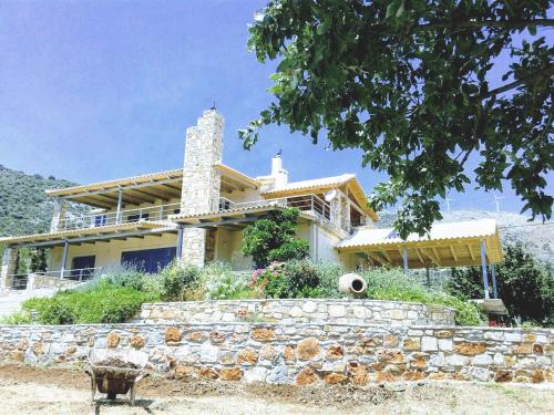 a house with a stone wall in front of it at blueline guesthouse in Áyios Dhimítrios