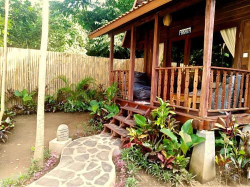 a wooden cabin with a porch and a fence at Ocean Prana Village in Amed