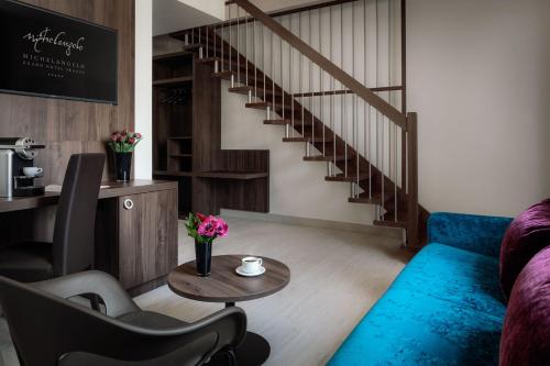 a living room with a blue couch and stairs at Michelangelo Grand Hotel in Prague