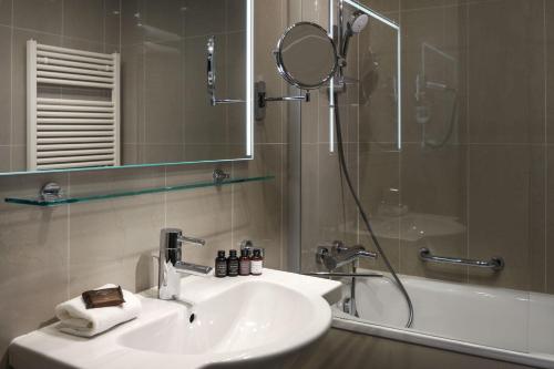 a bathroom with a sink and a shower with a mirror at Michelangelo Grand Hotel in Prague