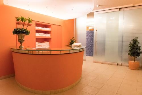 un vestíbulo con un mostrador circular en una sala de color naranja en relexa Hotel Ratingen City en Ratingen