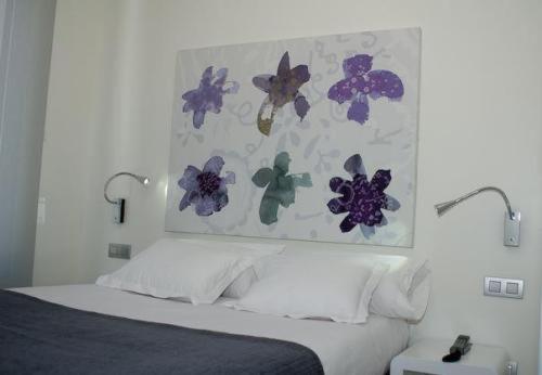 1 dormitorio con 1 cama con flores en la pared en Hostal Acuarela, en Burgos