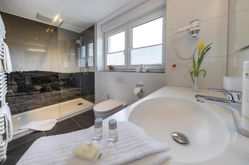a white bathroom with a tub and a sink at Gasthof - Hotel zum Ochsen GmbH in Blaubeuren