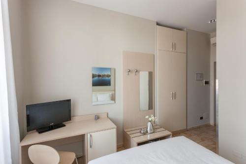 a room with a bed, desk, television and a refrigerator at Best Quality Hotel Dock Milano in Turin