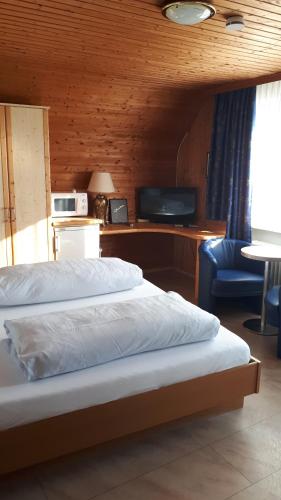 a bedroom with a bed and a tv and a chair at Hotel Restaurant Anna in Ramstein-Miesenbach