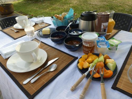 une table avec une assiette de fruits, de tasses et de cuillères dans l'établissement Les chambres du Ladoux, à Puy-de-Fourches