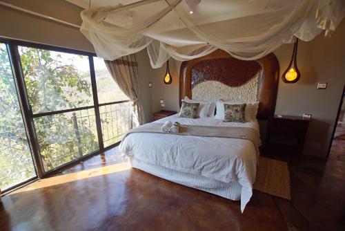 a bedroom with a large bed and large windows at Leopards Rock Bush Boutique in Bela-Bela
