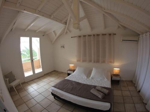 une chambre avec un grand lit avec deux lampes dans l'établissement Villa Iguanou et piscine en bord de mer proche plages marina et golf, à Saint-François