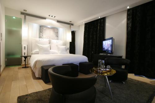 a hotel room with a bed and chairs and a television at Domaine de Verchant & Spa - Relais & Châteaux in Montpellier
