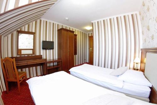 um quarto de hotel com duas camas e uma secretária em Hotel Zajazd Polonez em Tuczempy