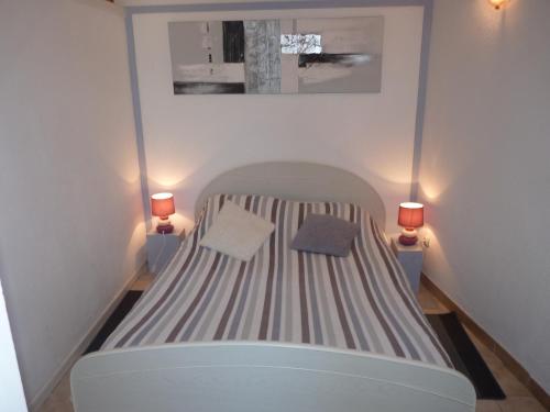 ein kleines Bett in einem Zimmer mit zwei Lampen in der Unterkunft Duplex T2 mezzanine, Saint Pierre la Mer in Saint Pierre La Mer