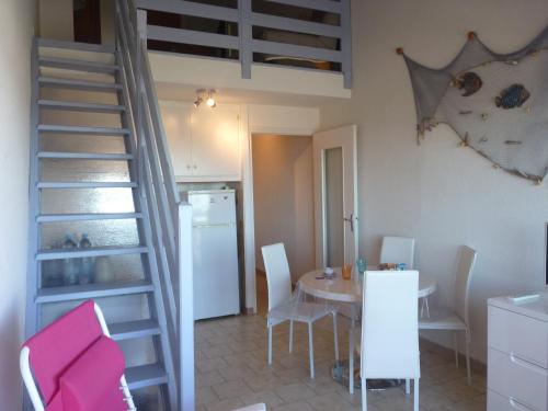 eine Küche und ein Esszimmer mit einer Treppe und einem Tisch in der Unterkunft Duplex T2 mezzanine, Saint Pierre la Mer in Saint Pierre La Mer