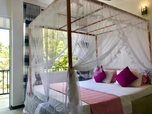 a bedroom with a canopy bed with pink pillows at Aluthgedara Guest House in Unawatuna
