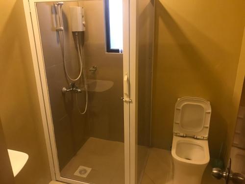 a bathroom with a shower and a toilet at Babylon Oslob Coast Guesthouse in Oslob