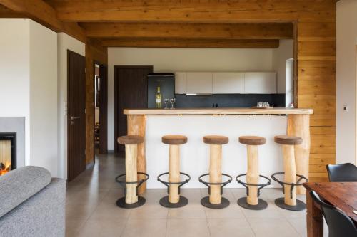 a kitchen with a bar with four stools at Chata Hrozenka WELLNESS in Nový Hrozenkov