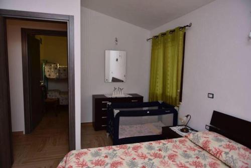 1 dormitorio con cama, escritorio y cortina verde en Su Cuccureddu ONIFAI, en Onifai